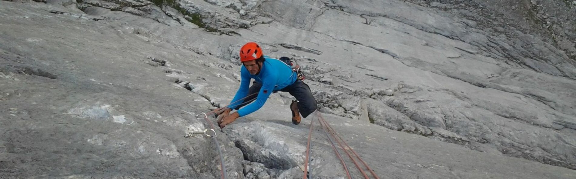 Kletterer in einer Felswand mit Seilen gesichert.