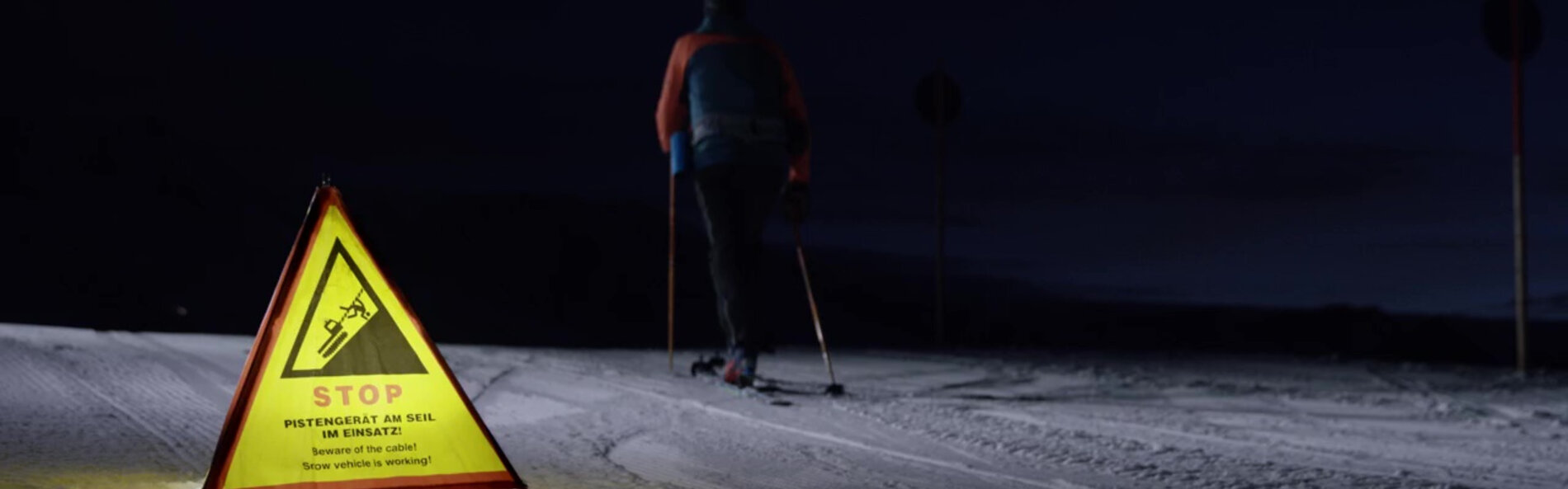 Tourer ignores warning notice on ski slope at night.