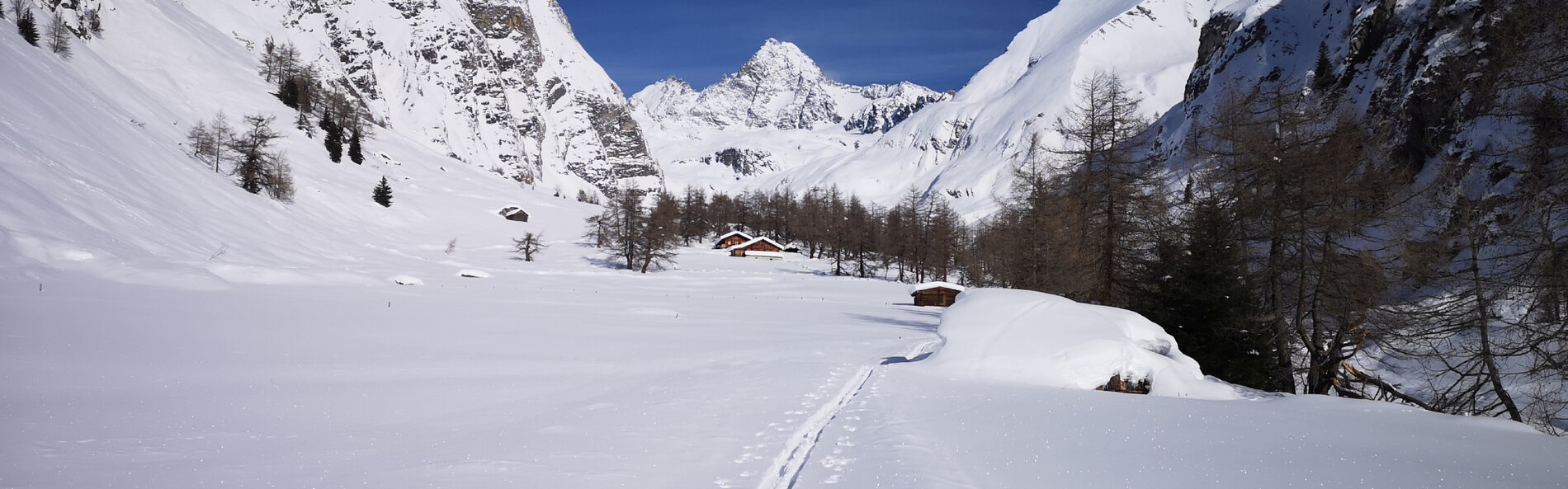 Blick ins tief verschneite Ködnitztal. Eine Skispur führt in Richtung mehrerer kleiner Hütten. Im Hintergrund der Großglockner. © NPHT, Kurzthaler