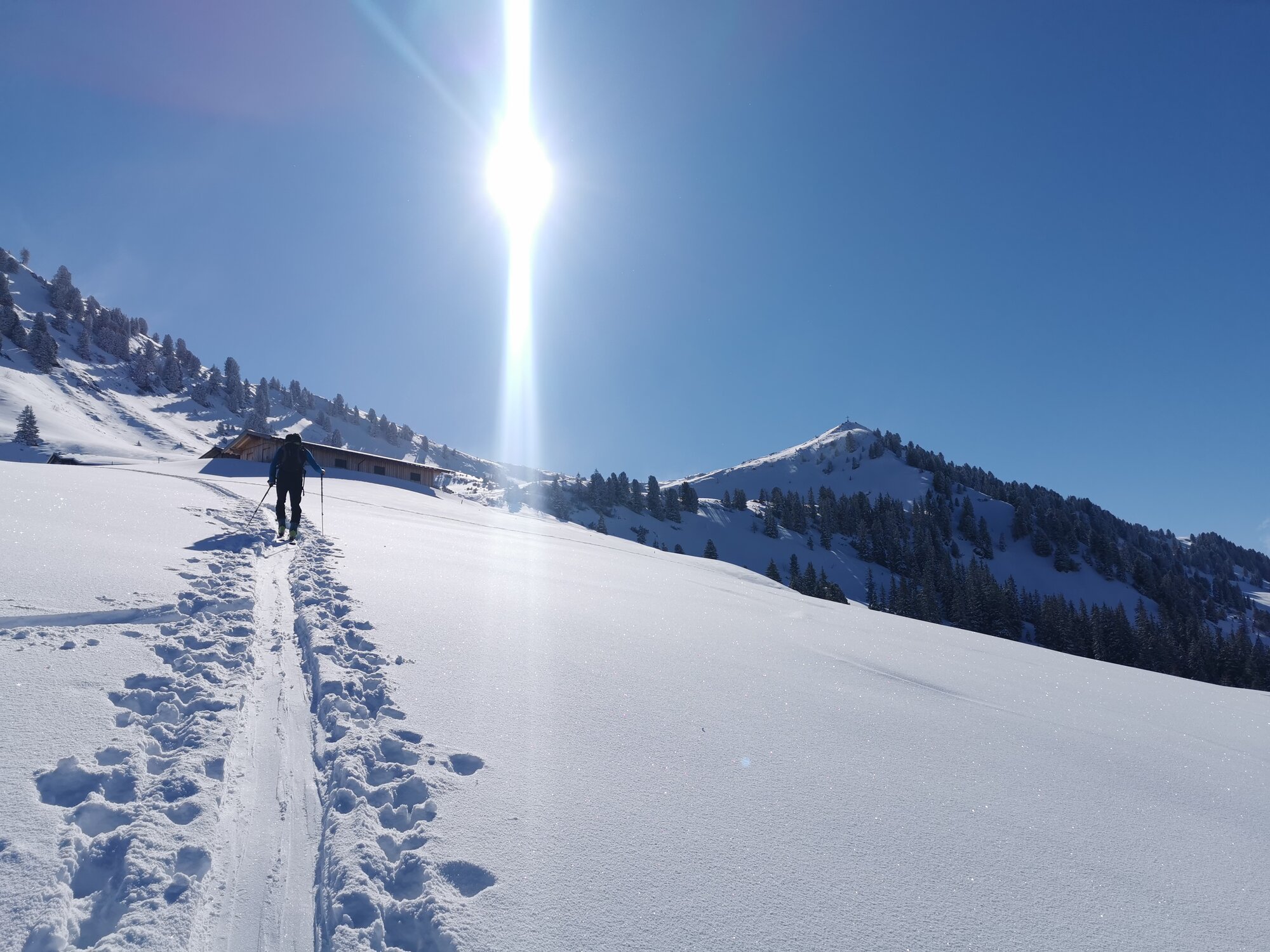 Tourers follow a trail through a deep snow slope towards the summit in bright sunshine. © C. Silberberger, Wildschönau Tourism 