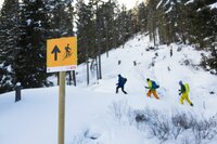 Leitsystemschild Aufstieg. Tourengeher im Hintergrund