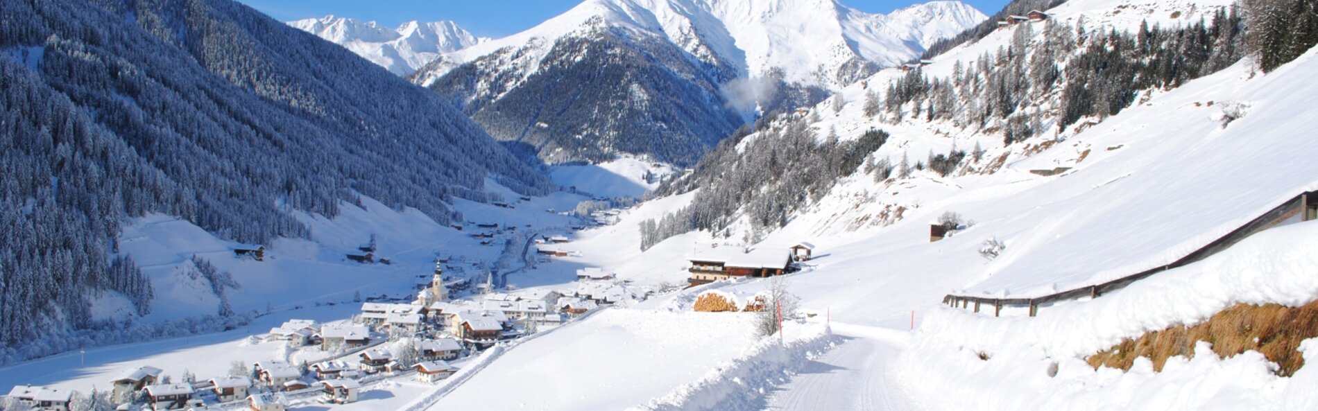 Snowy valley road with village