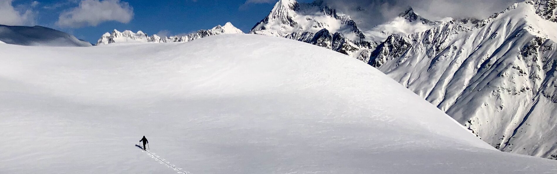 Skitourengeher im Aufstieg auf einer eibgeschneiten Bergflanke mit weißen Bergen im Hintergrund ©Thomas Zimmermann