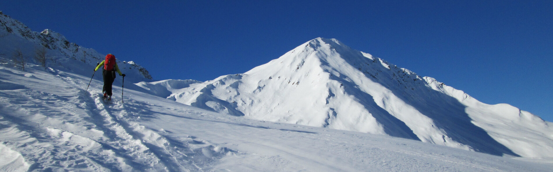 Skitourengeher geht in Richtung eines tief winterlich verschneiten Bergs. © TVB Osttirol, F. Steiner 