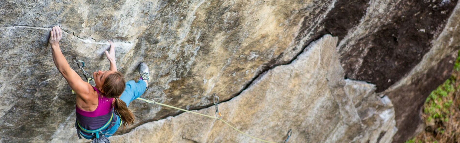 Woman climbing a bare rock wall.