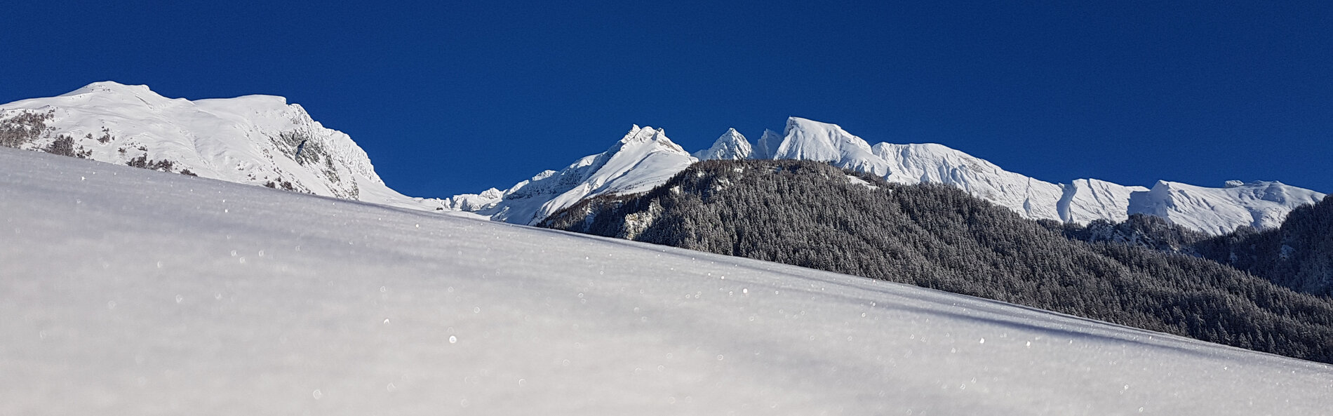 Winterlandschaft. Im Vordergrund glitzernder Schnee. Im Hintergrund eine verschneite, sonnenbeschienene Bergkette © TVB Osttirol, B. Assmair