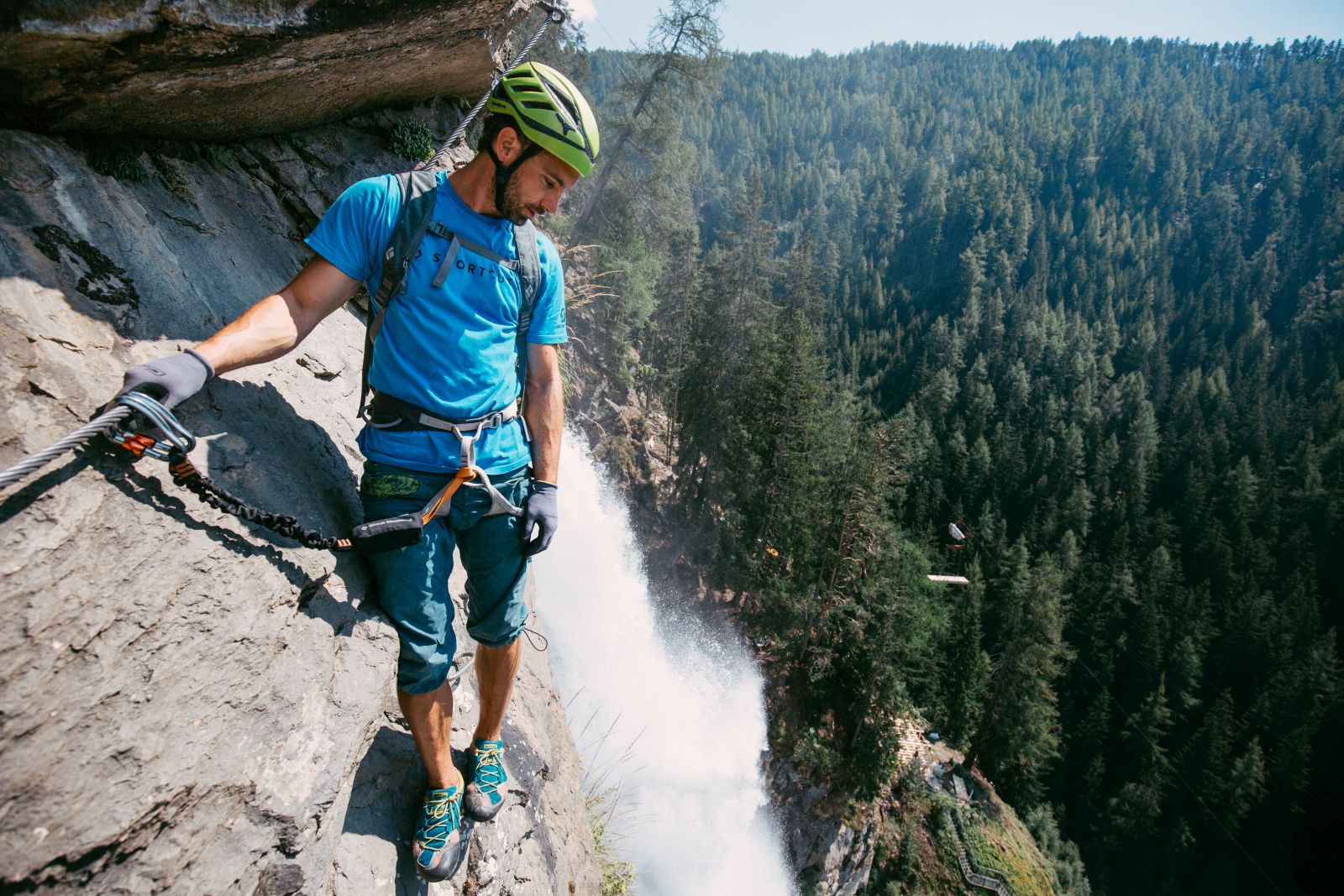 Man in via ferrata before waterfall