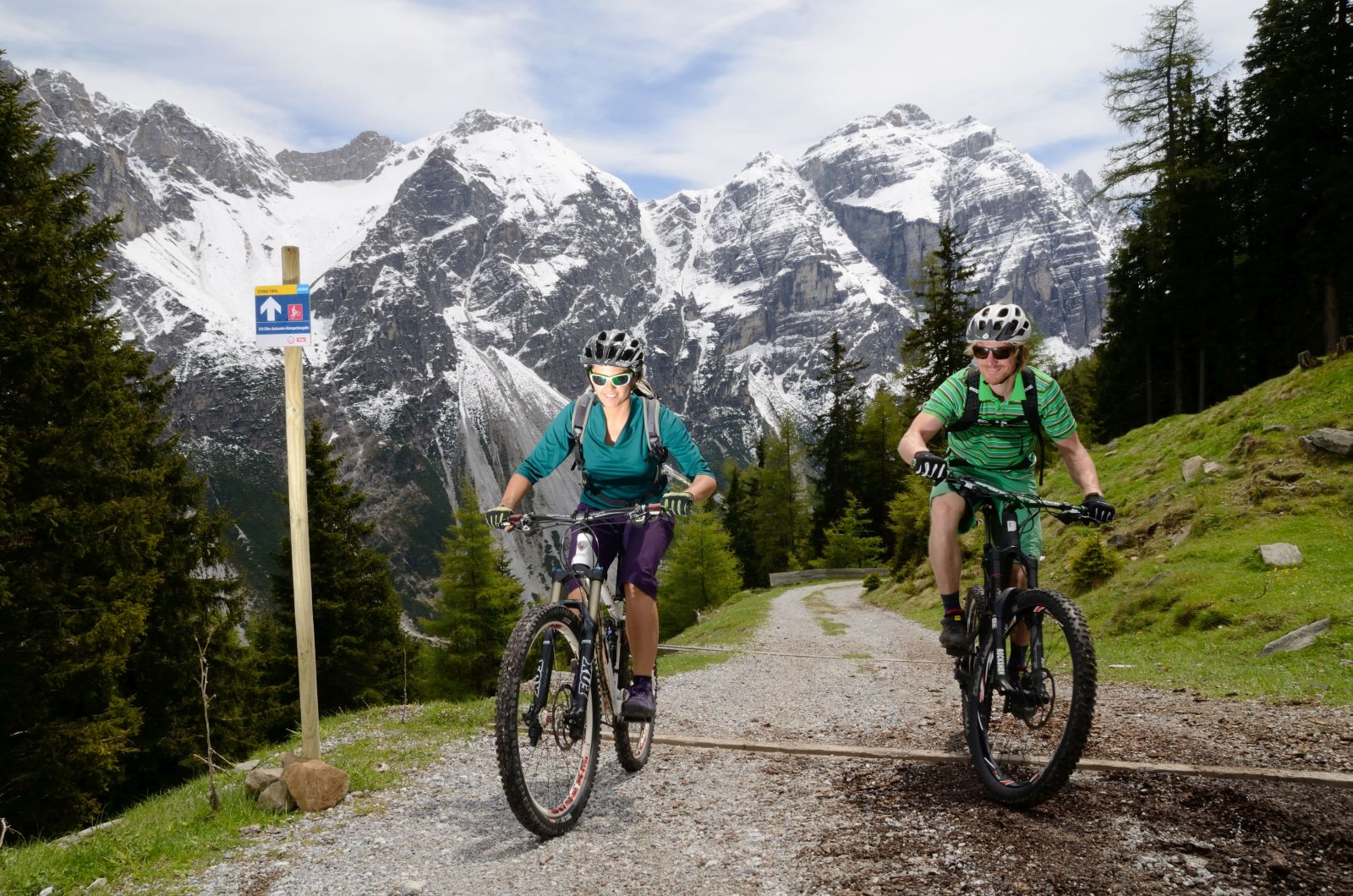 2 mountain bikers on forest road, nationwide signage with direction sign